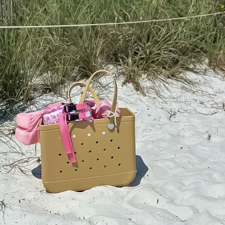 Beige handbag with pink ribbon on a sandy beach